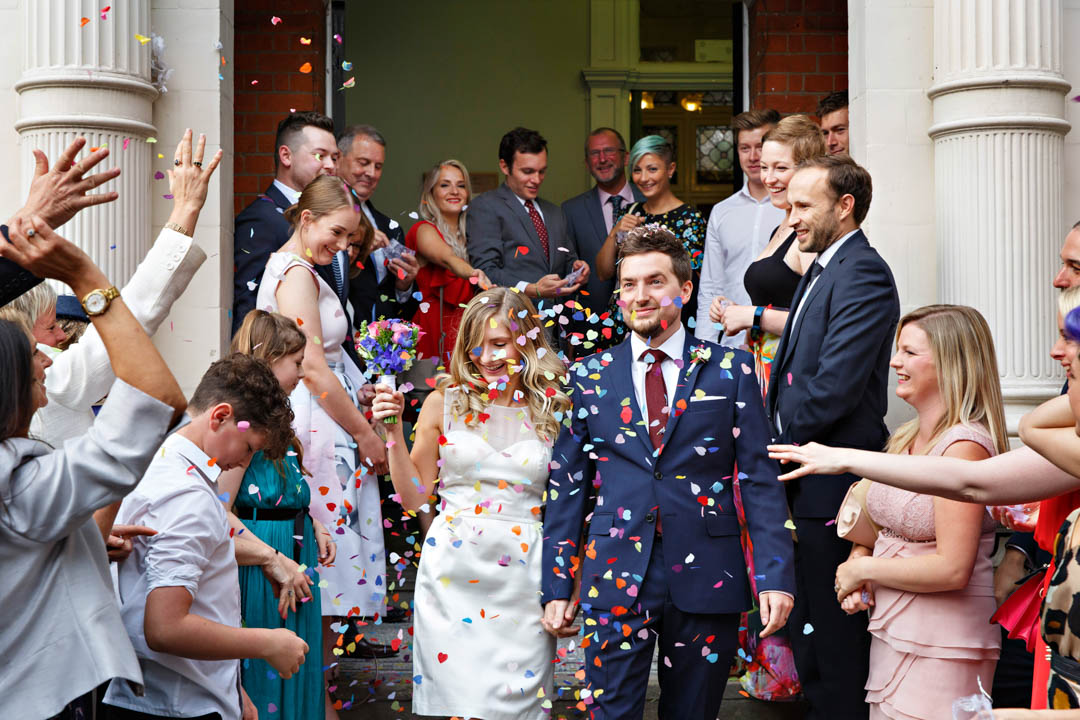 Newlyweds are covered in confetti on the steps of Mayfair Library in celebration of becoming husband and wife during their Westminster register office wedding.